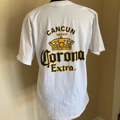 Corona Tee Shirt Size Medium From Cancun Never Worn Excellent Condition Summer Fan Apparel T-shirt With Logo Print, Summer Fan Apparel Tops With Logo Print, Summer Logo Print Fan Apparel Tops, White Relaxed Fit T-shirt For Fans, White Print Crew Neck Shirt With Logo, Casual Shirt With White Logo Print, White Cotton Shirt For Fan Merchandise, Casual White Shirt With Logo Print, Casual White Print Shirt With Logo