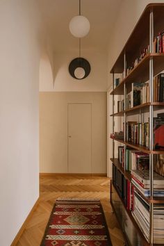 a long narrow room with bookshelves and a rug on the floor in front of it