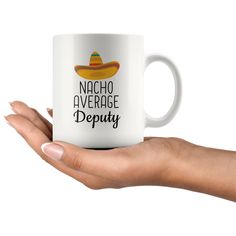 a woman's hand holding a white coffee mug that says nacho average betie