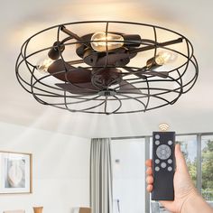 a person holding a remote control up to a ceiling fan that is mounted on the ceiling