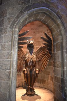 a statue of a bird sitting on top of a stone wall next to a doorway