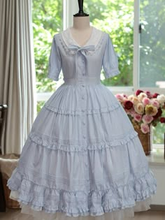 Step into the world of timeless charm with our Blue Front Button Placket Classic Lolita Dress. This exquisite piece is designed to capture the essence of classic Lolita fashion, featuring intricate ruffle trim and delicate pleating details that exude sophistication and grace.  The dress boasts a beautifully crafted front button placket, adding a touch of vintage allure, while the rich purple hue brings a regal elegance to your wardrobe. The removable bowtie on the neckline offers versatility, al Blue Victorian Dress, Vintage Blue Dress, Victoria Style, Country Lolita, Sailor Outfit, Vintage Dress Blue, Regal Elegance, Victoria Fashion, Classic Lolita