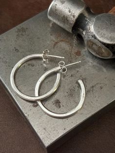 These simple, minimalist hoops are the perfect size for everyday wear. They're hand forged from recycled 925 Sterling silver and have 925 Sterling silver posts and push back closures.  Measurments are 2cm width x approx 2mm thickness  Finish is raw / brushed silver. They can be oxidized to have a blackened / grayish patina (not shown but you can see this finish in other items in my shop) choose your finish from the drop down menu at checkout.  Please read shop policies before ordering.  All jewelry from my studio will arrive attractively packaged and ready for gifting or keeps. Minimalist Hand Forged Small Hoop Earrings, Minimalist Hand Forged Earrings For Everyday, Minimalist Handmade Hoop Earrings, Everyday Minimalist Hand Forged Earrings, Small Hoop Hand Forged Everyday Earrings, Minimalist Hammered Hoop Earrings For Everyday, Everyday Small Hoop Hand-forged Earrings, Hand Forged Small Hoop Earrings For Everyday, Everyday Small Hoop Hand Forged Earrings