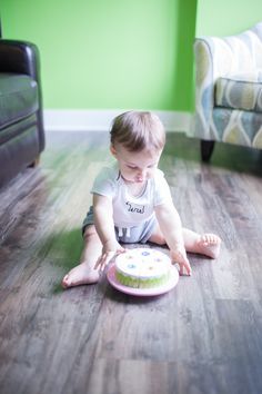 a small child sitting on the floor with a cake