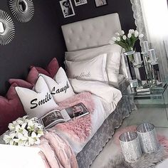 a bedroom with black walls and white bedding is decorated in shades of pink, grey and silver