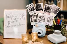 polaroid camera sitting on top of a wooden table next to pictures and candles in front of it