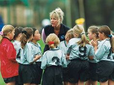 a group of young women standing next to each other on top of a soccer field