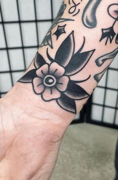 a black and white flower tattoo on the left arm, with music notes in the background