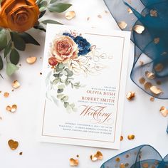 a wedding card with flowers and gold confetti on it next to blue organes