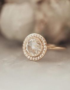 a close up view of a diamond ring on a white surface with rocks in the background