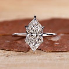 a diamond ring sitting on top of a wooden table next to a brown maple leaf