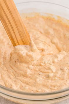 a wooden spoon mixing batter in a glass bowl