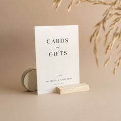 a white card with the words cards and gifts on it sitting next to a rock