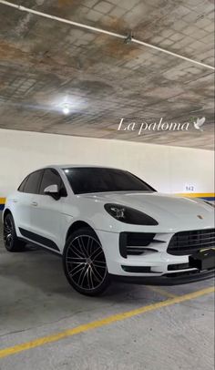 a white porsche cayen is parked in a parking garage with yellow lines on the floor