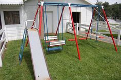 a swing set and slide in front of a house