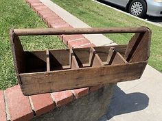 a wooden basket sitting on the side of a sidewalk next to a car parked in front of a house