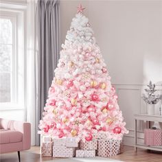 a pink and white christmas tree in a living room with presents on the floor next to it