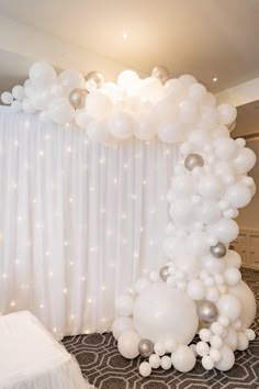 a balloon arch in the middle of a room with white and silver balloons on it