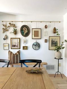 a dining room table with chairs and pictures hanging on the wall above it's head