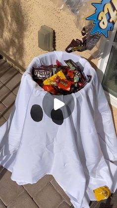 a white ghost bag filled with candy sitting on top of a brick floor next to a window