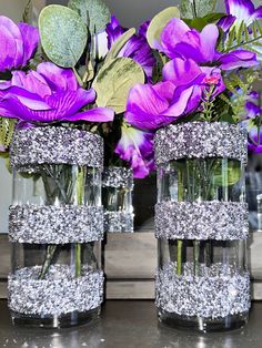 two clear vases with purple flowers in them