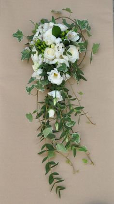 a bouquet of white flowers and greenery is laying on a tableclothed surface