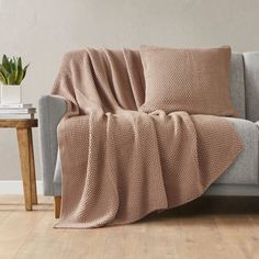 a couch with a blanket on top of it next to a table and potted plant