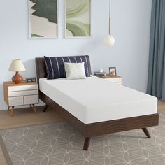 a bed with a wooden frame and white mattress in a blue room next to two pictures on the wall