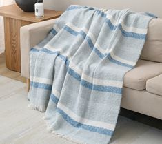 a blue and white striped blanket sitting on top of a couch next to a vase