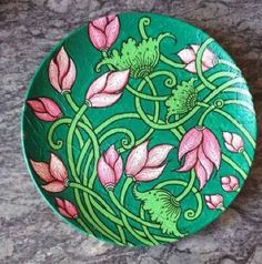 a green plate with pink flowers on it sitting on a stone counter next to a wall