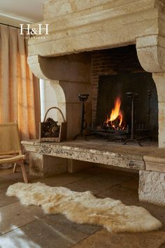 a stone fireplace in a living room with an animal rug on the floor next to it