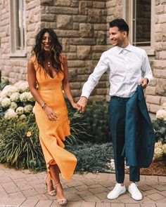 a man and woman holding hands while walking down the street