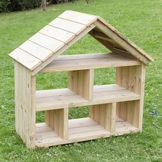 a wooden doll house sitting in the grass