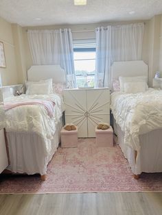 two white beds in a bedroom next to a window