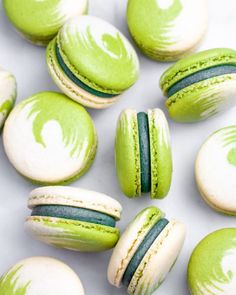 green and white macaroons are arranged on a table