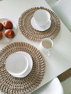 the table is set with plates, cups and fruit on it's placemats