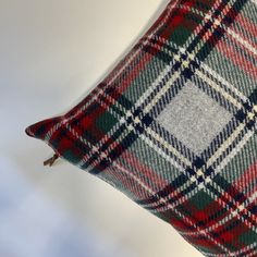 a red, white and green plaid pillow on a table