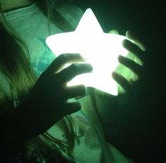 a person holding a lit up star in their hands