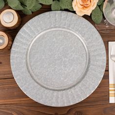 a white plate sitting on top of a wooden table next to silverware and flowers