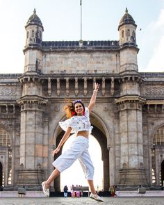 a woman is jumping in front of an old building