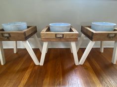 three wooden bowls sitting on top of two stands in the middle of a wood floor