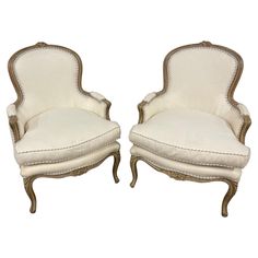 two white chairs with gold trimmings on the back and arms, one is upholstered