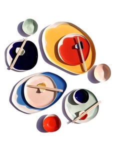 an assortment of colorful plates with chopsticks and saucers