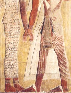 two ancient egyptian men standing next to each other in front of a wall painting on the side of a building