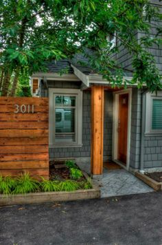 a small gray house with trees in the front yard and number 101 on the door