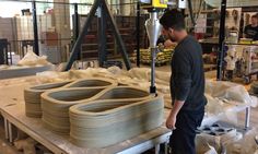 a man standing in front of stacks of plates on a workbench at a factory