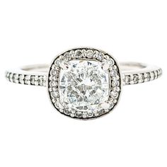 an engagement ring with a cushion cut diamond in the center and pave set shoulders