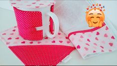 a pink and white cup sitting on top of a table next to two napkins