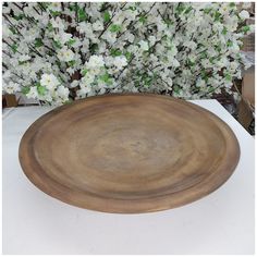 a wooden plate sitting on top of a table next to a vase with white flowers