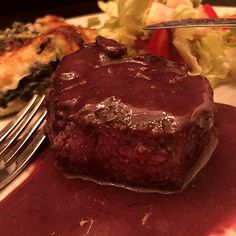 a piece of meatloaf on a plate with a fork and salad in the background